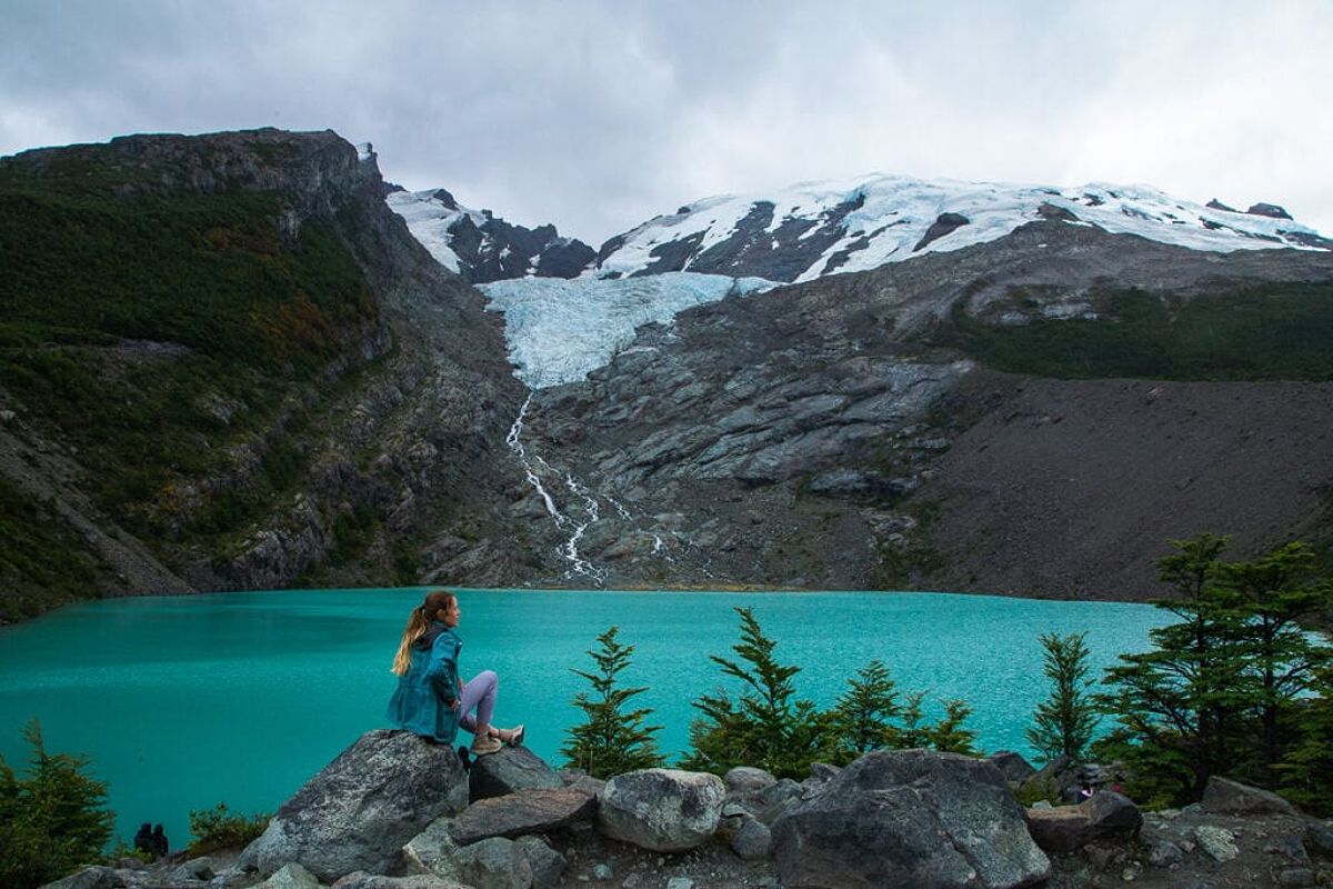 Hiker in front of a turquoise glacier lake