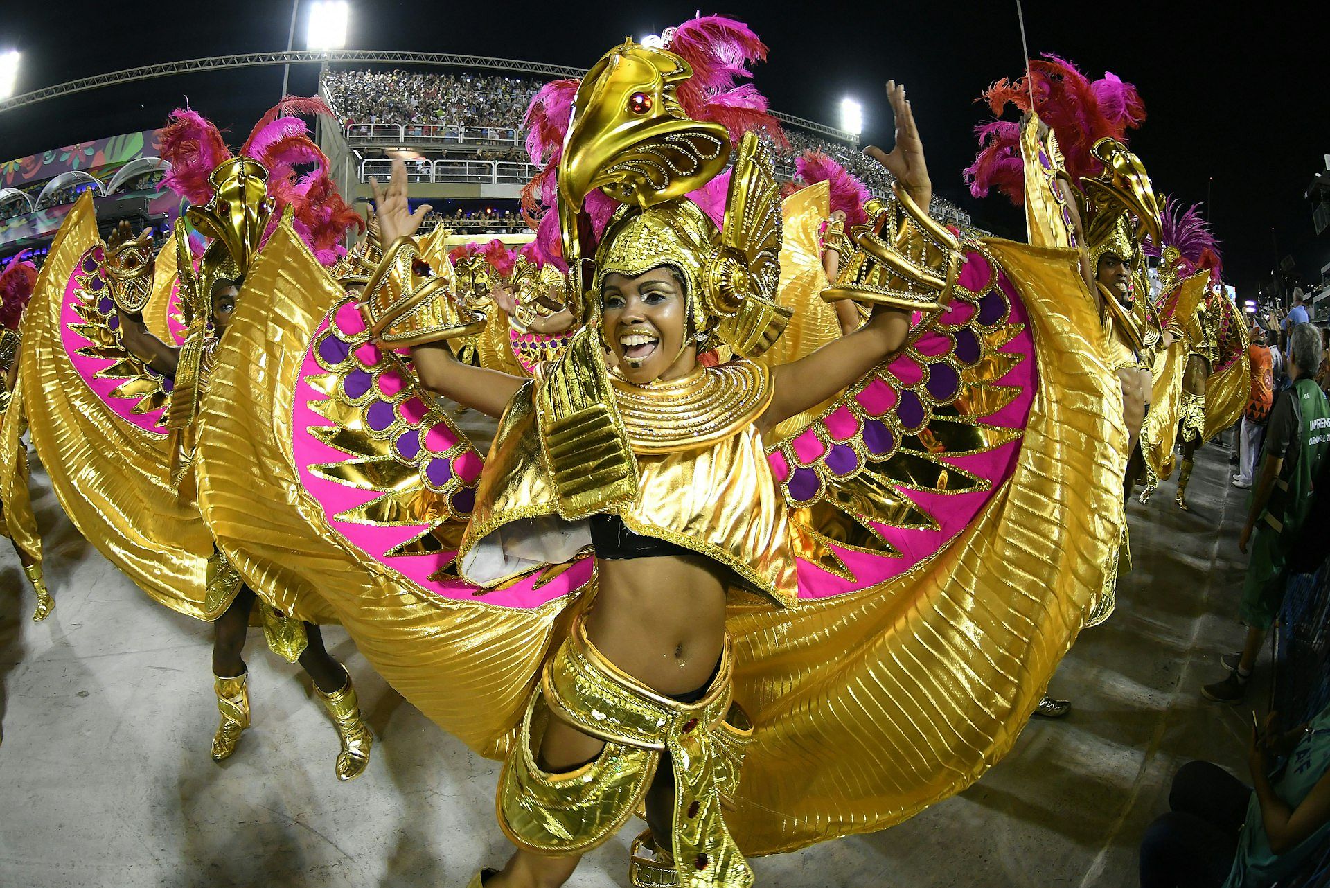 Women dance in elaborate gold costumes at the Parade of the Samba Schools during the Carnival of Rio de Janeiro